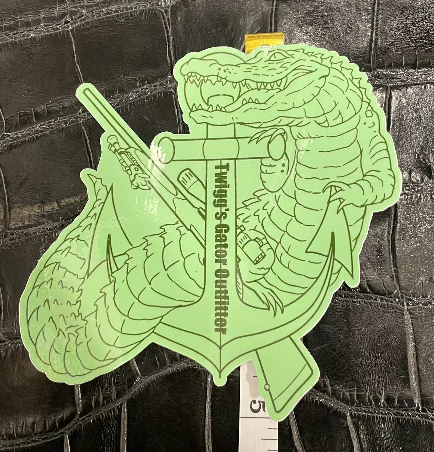 Green alligator-shaped object with text on a textured black background