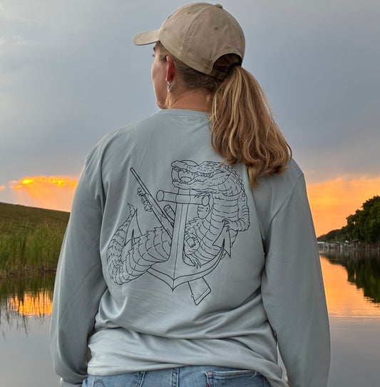 Person wearing a light gray shirt with a graphic design, standing near a reflective surface.