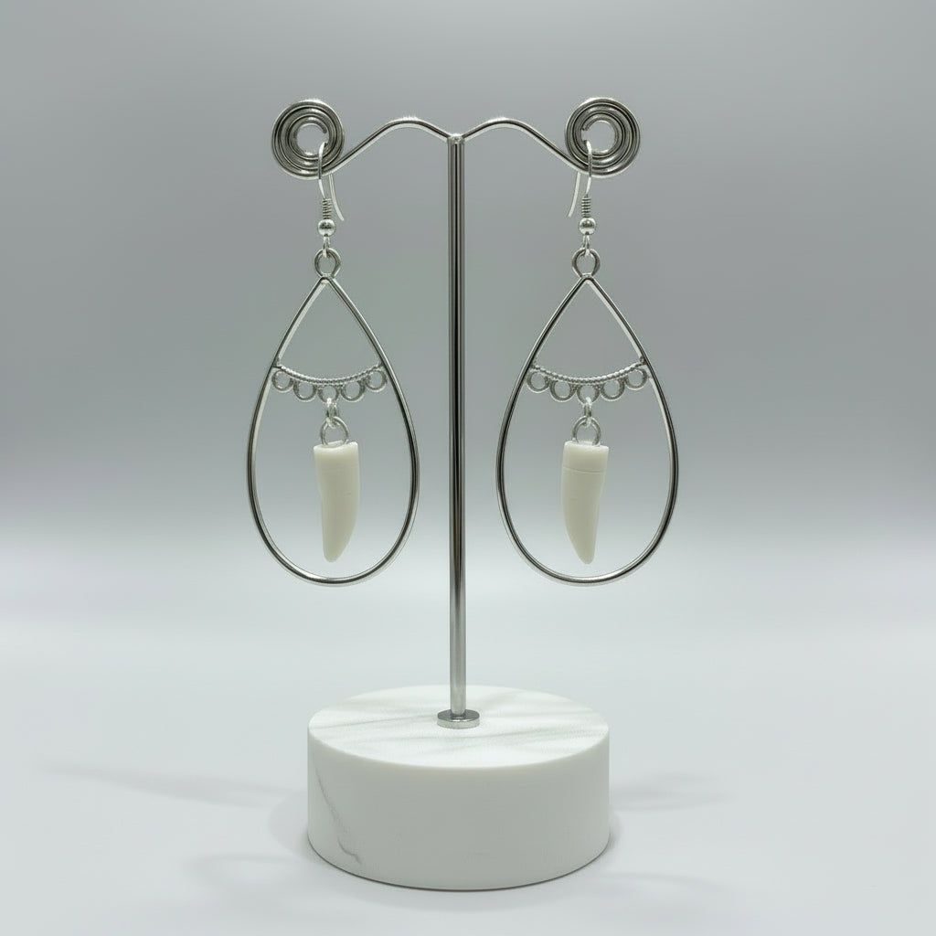Silver teardrop earrings with white alligator tooth pendants on a blue background