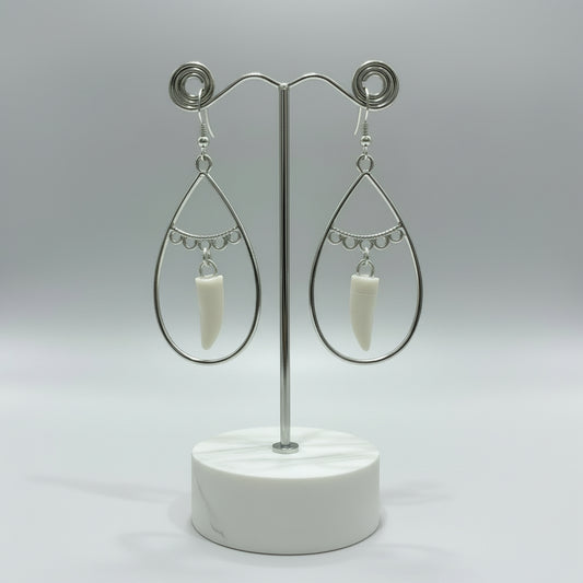 Silver teardrop earrings with white alligator tooth pendants on a blue background