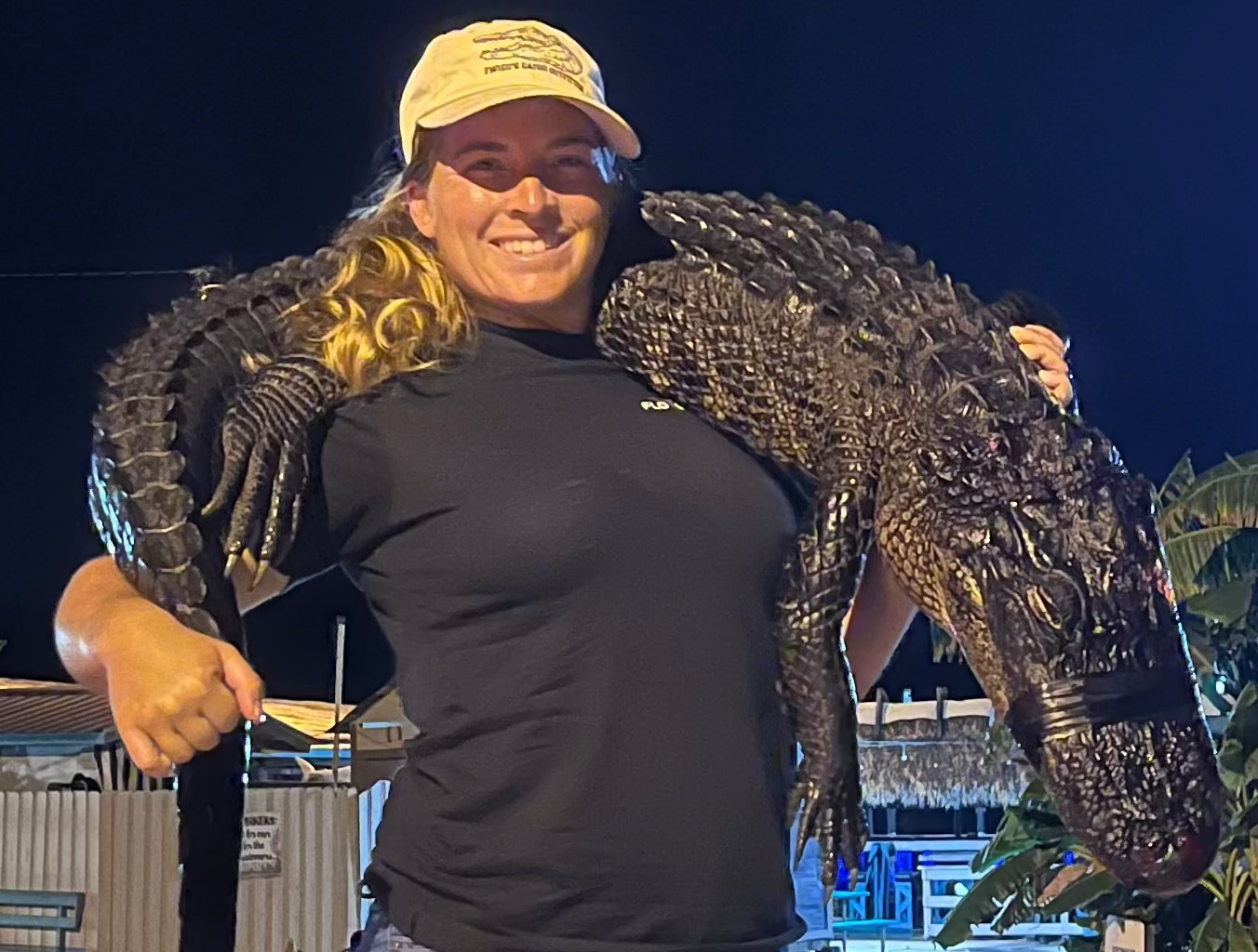 Person holding a large alligator at night.